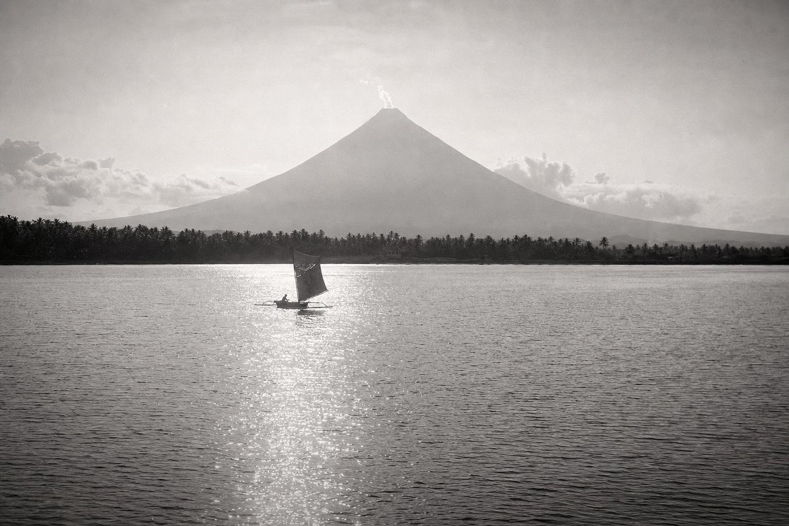 Mt. Mayon across the Gulf of Albay at dusk, a lone outrigger banca under sail